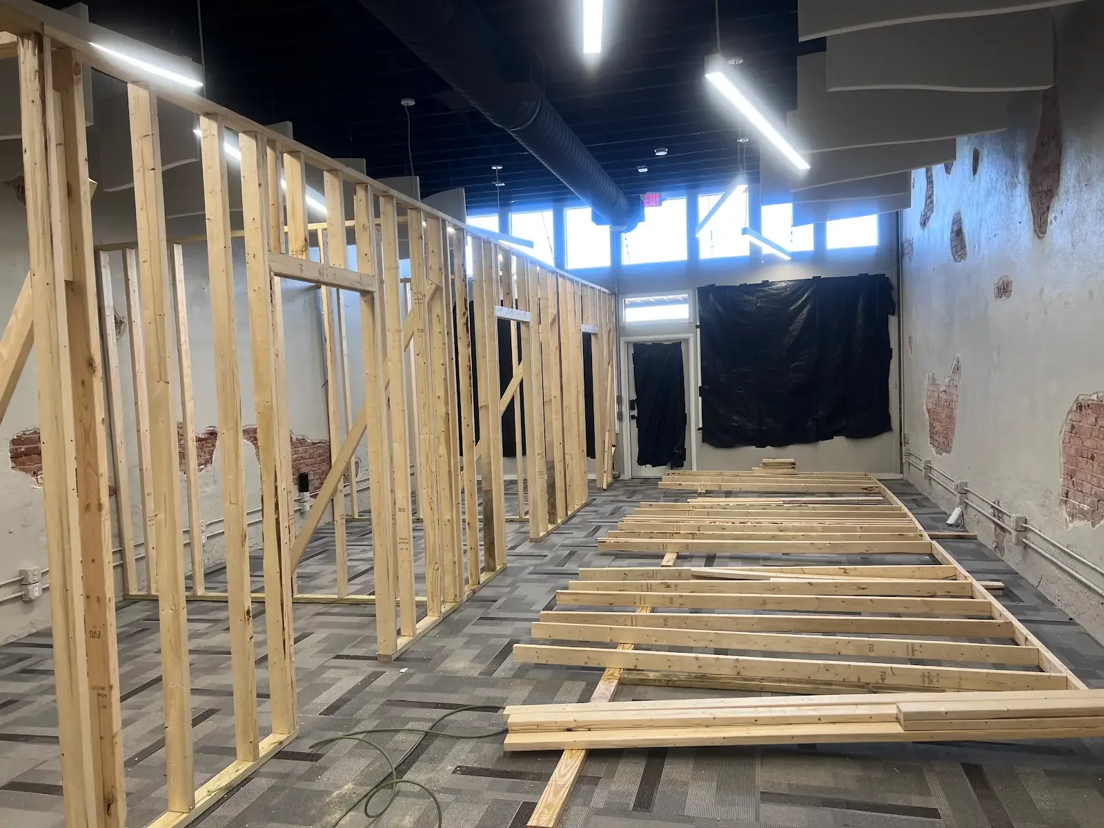 Timber wall framing and wall sections laid out on the floor inside a building